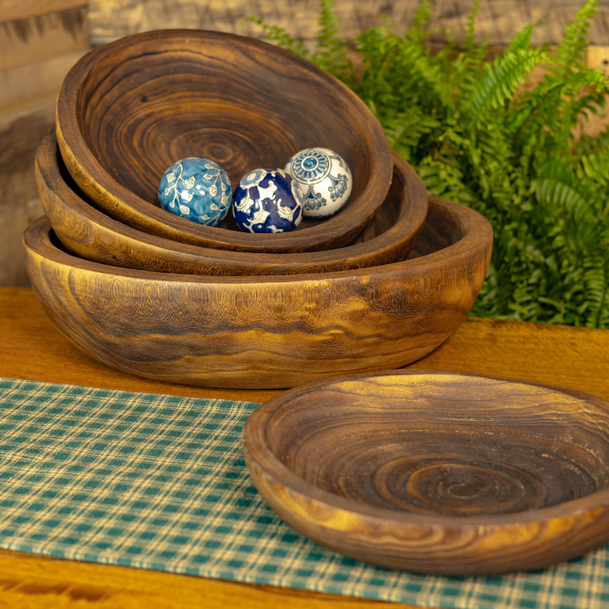 Nested wooden trays sit behind a separate empty tray, with three patterned balls in the stack.