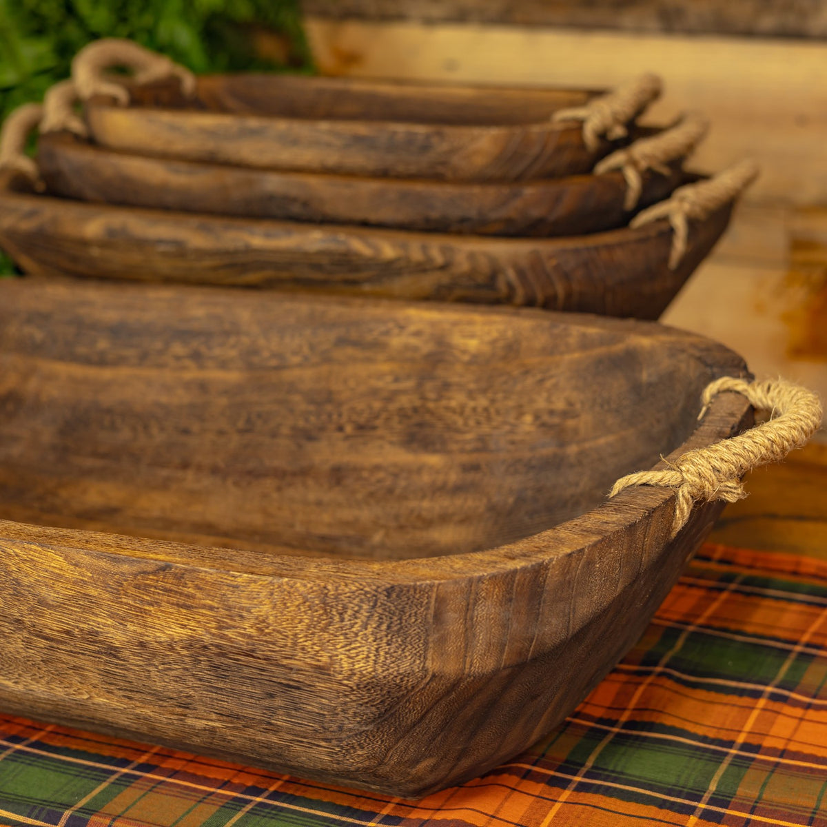 Four oval wooden trays nested together, with textured surfaces and rope handles.