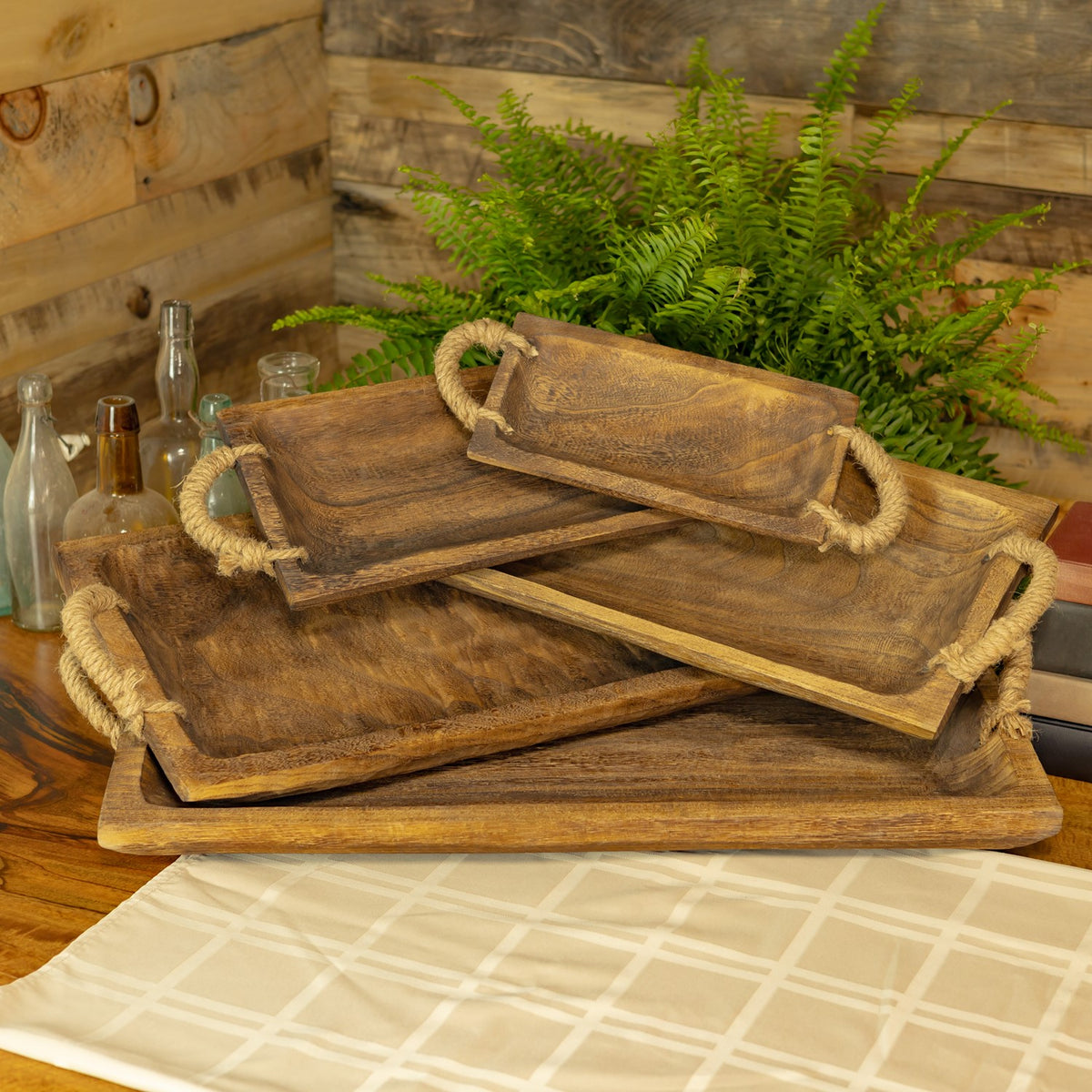 Brown wooden trays with rope handles stacked in a display