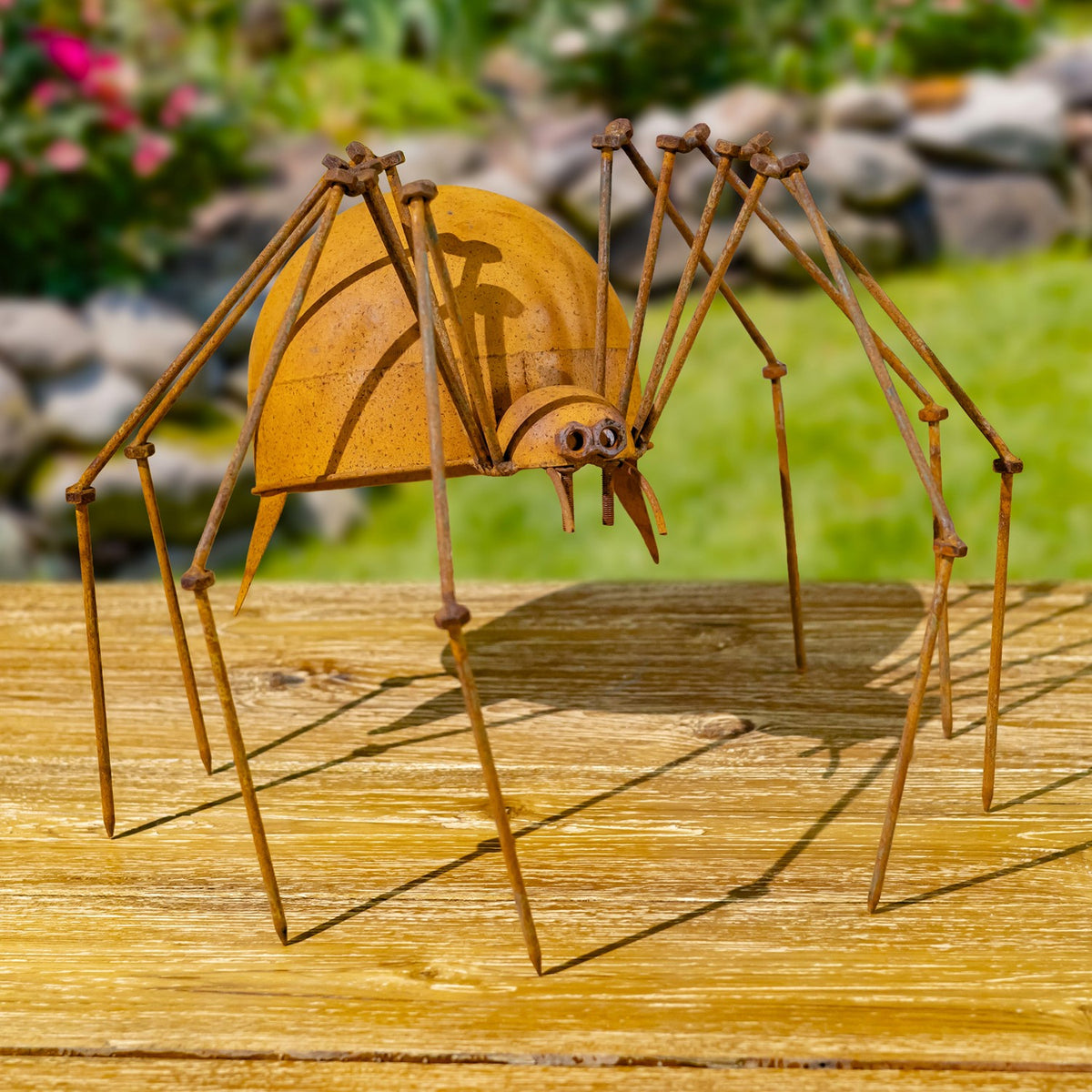 Rust-finish iron spider figurine shown from the front on a wooden surface