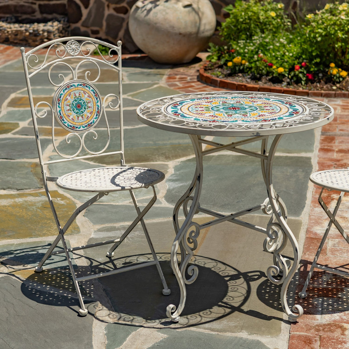 Closer view of the mosaic tabletop and one decorative chair, with part of the second chair at right.