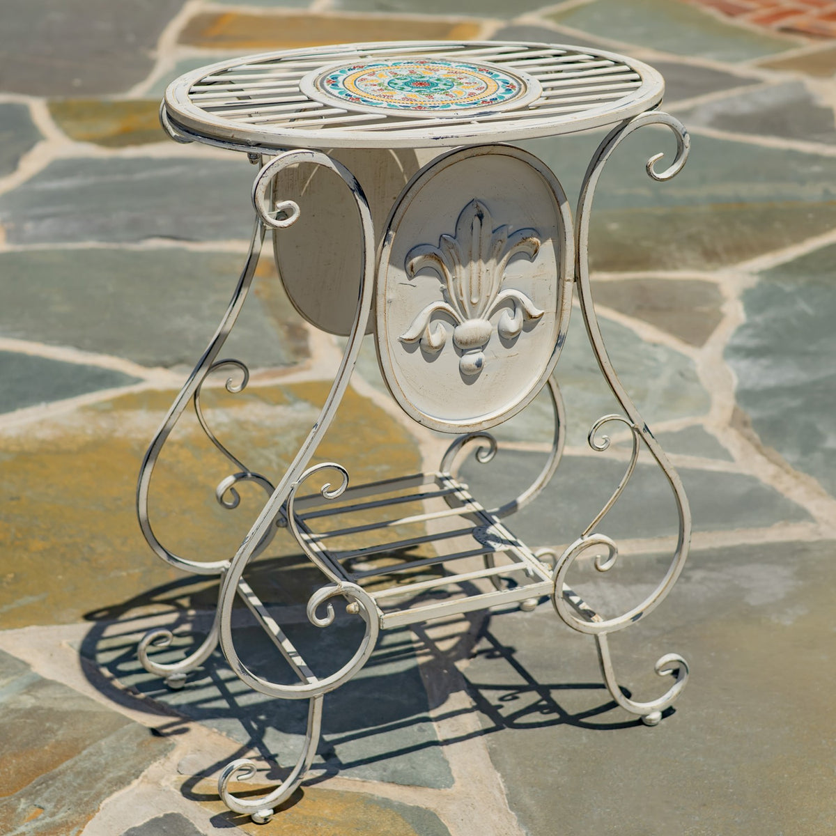 One cream plant stand shown close up, with curled metal legs and a raised floral medallion.