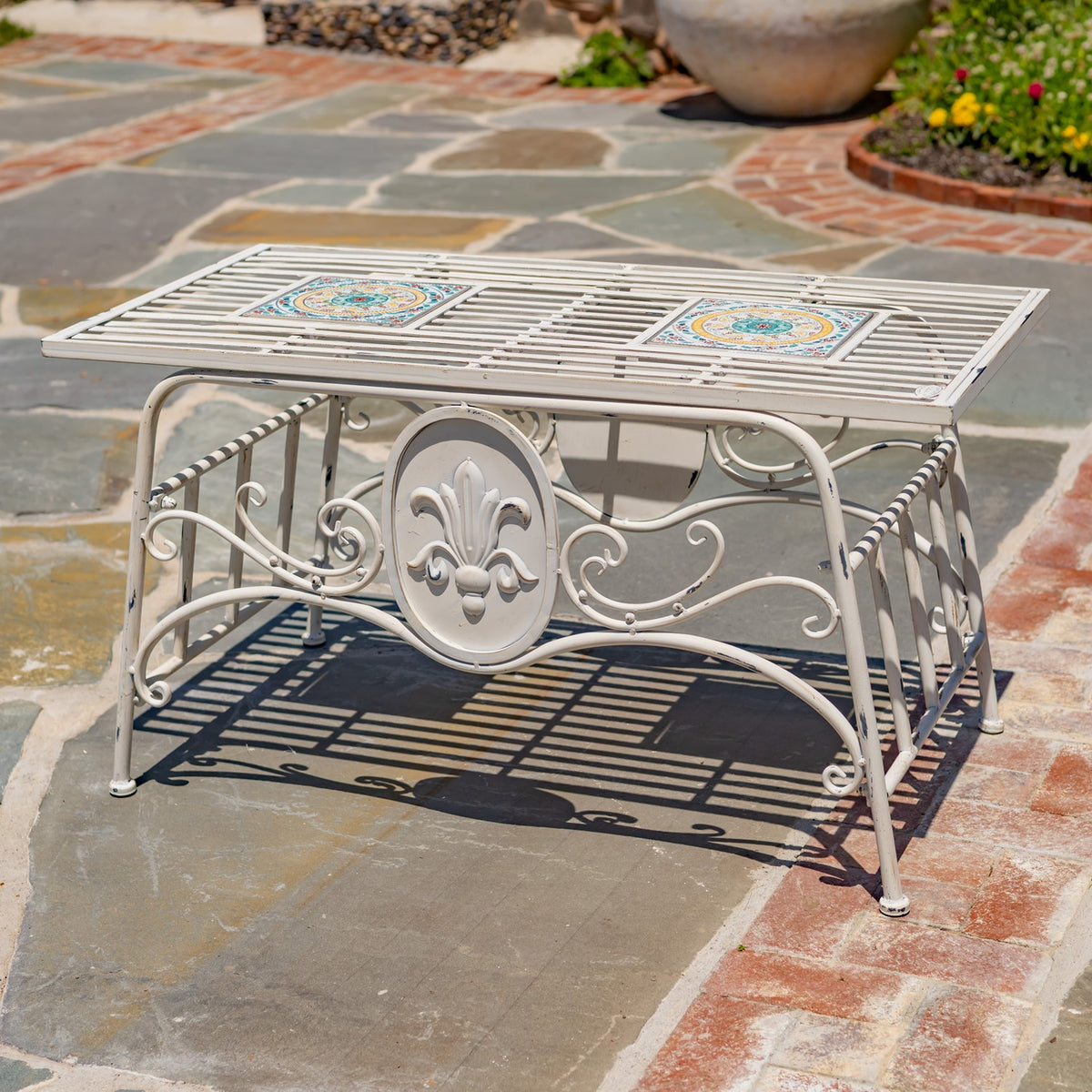 White metal table shown without a plant, with two colorful mosaic panels and ornate scrollwork.