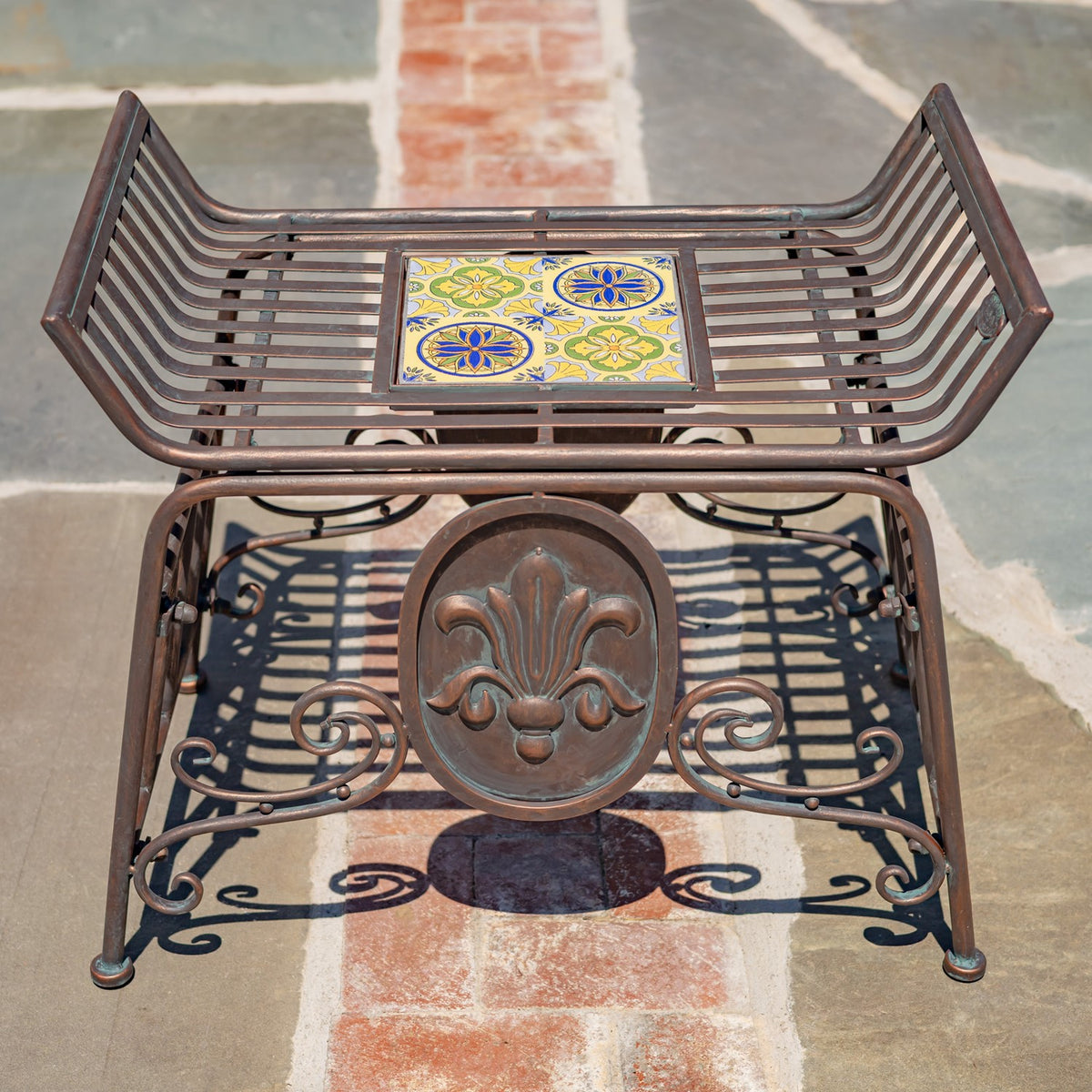Elevated view of the chair shows its slatted seat, square mosaic tile, and decorative front medallion.