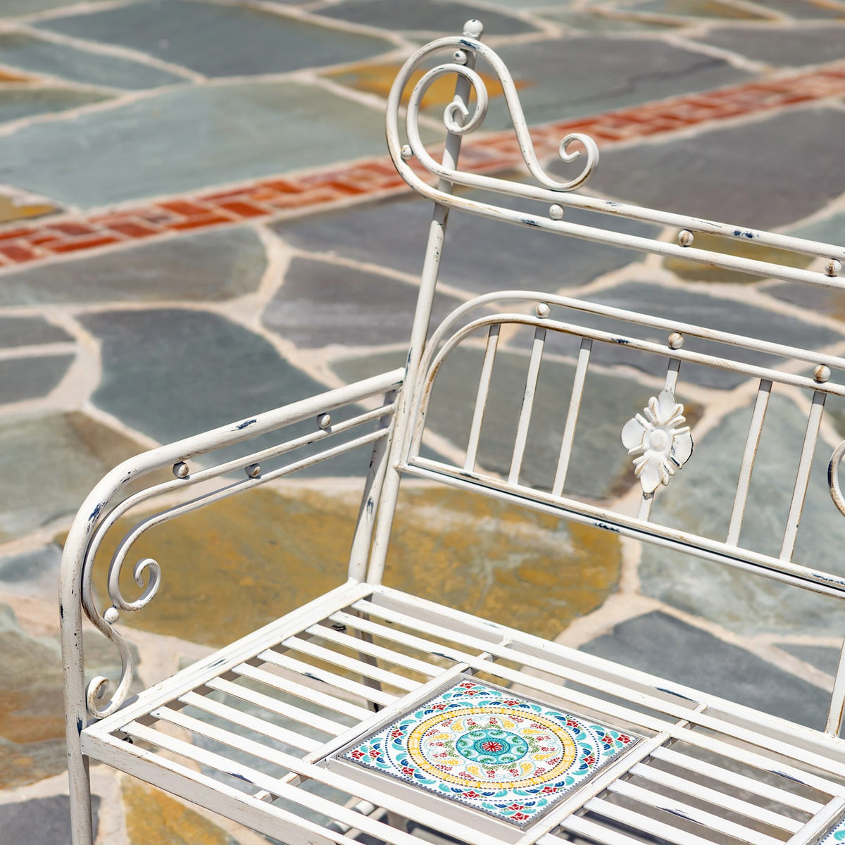 Close view of the bench’s curled armrest, metal slats, and colorful mosaic seat tile