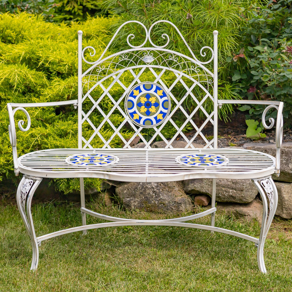 Front-facing view of an ornate white bench with patterned mosaic tiles on its back and seat.