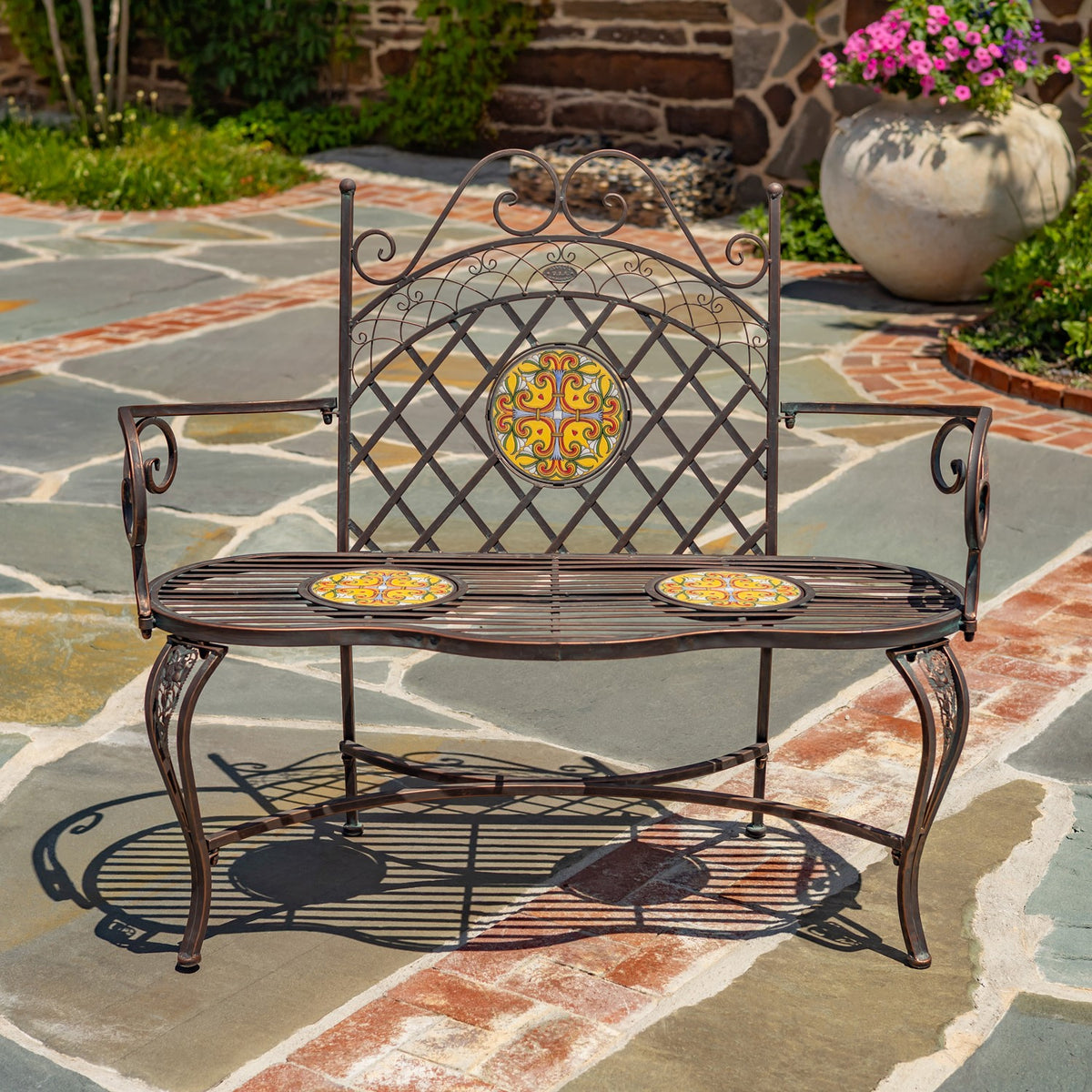 Garden bench shown straight on, with curled metal arms and three colorful mosaic panels.