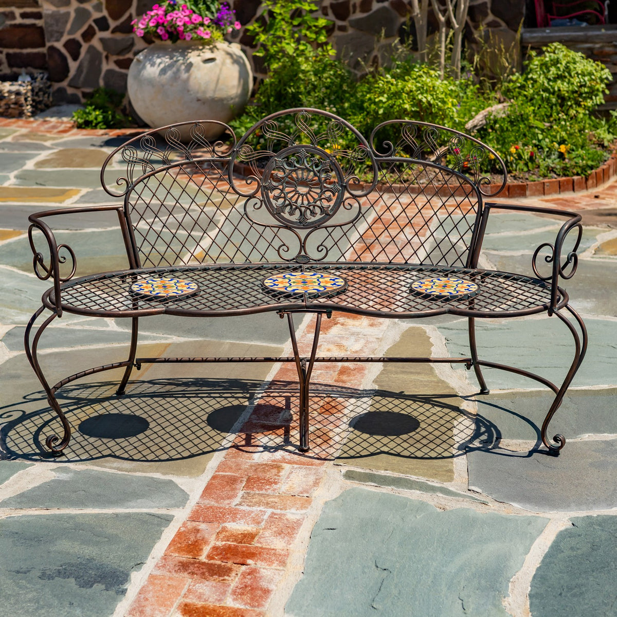 Front view of a garden bench showing its scrollwork back, curved arms, and three mosaic seat tiles.