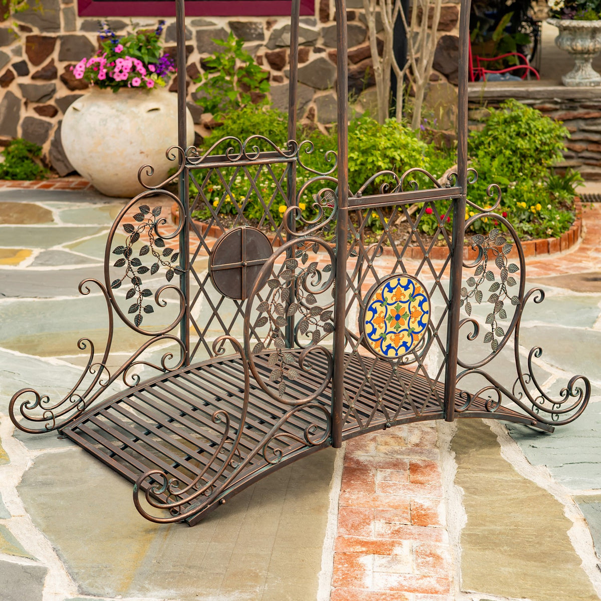 Close view of the bridge’s slatted floor, curled metalwork and colorful circular mosaic panel.