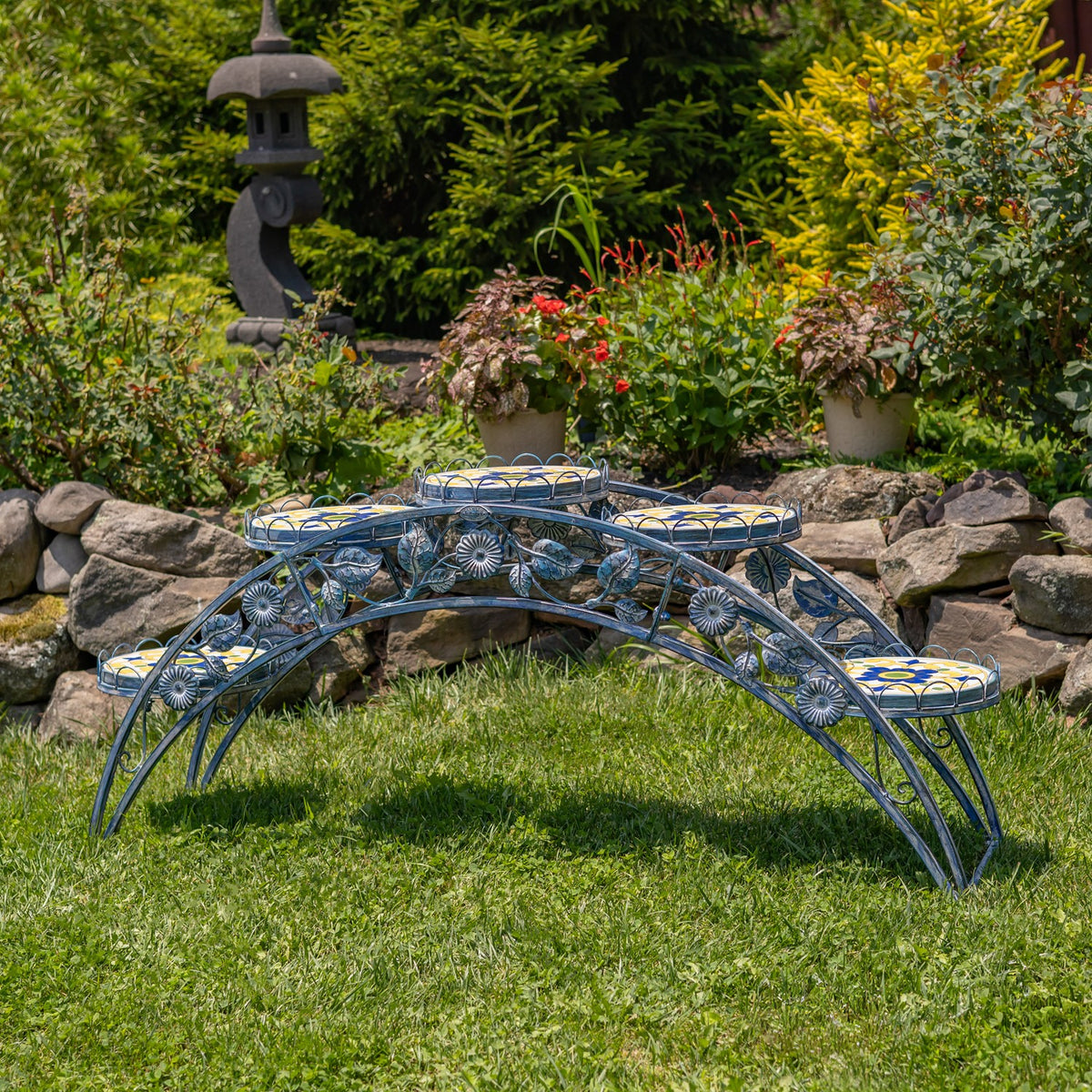 Blue arched plant stand shown without pots, with five round mosaic platforms in a garden.