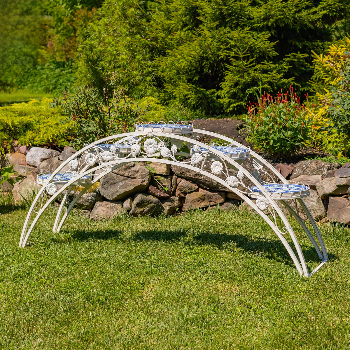 Side view of the curved white iron stand, with decorative floral scrollwork and mosaic-topped platforms.