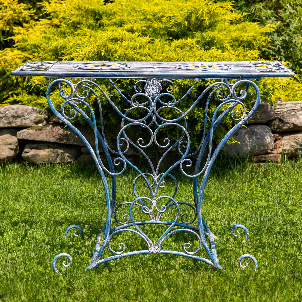 Full view of the blue iron table’s long mosaic surface and symmetrical curling metal base.