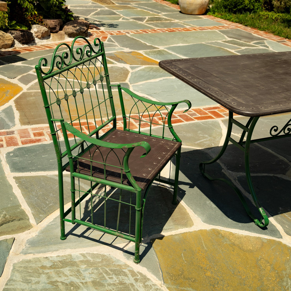 Close view of a green scrollwork chair with a brown seat beside the dark tabletop.