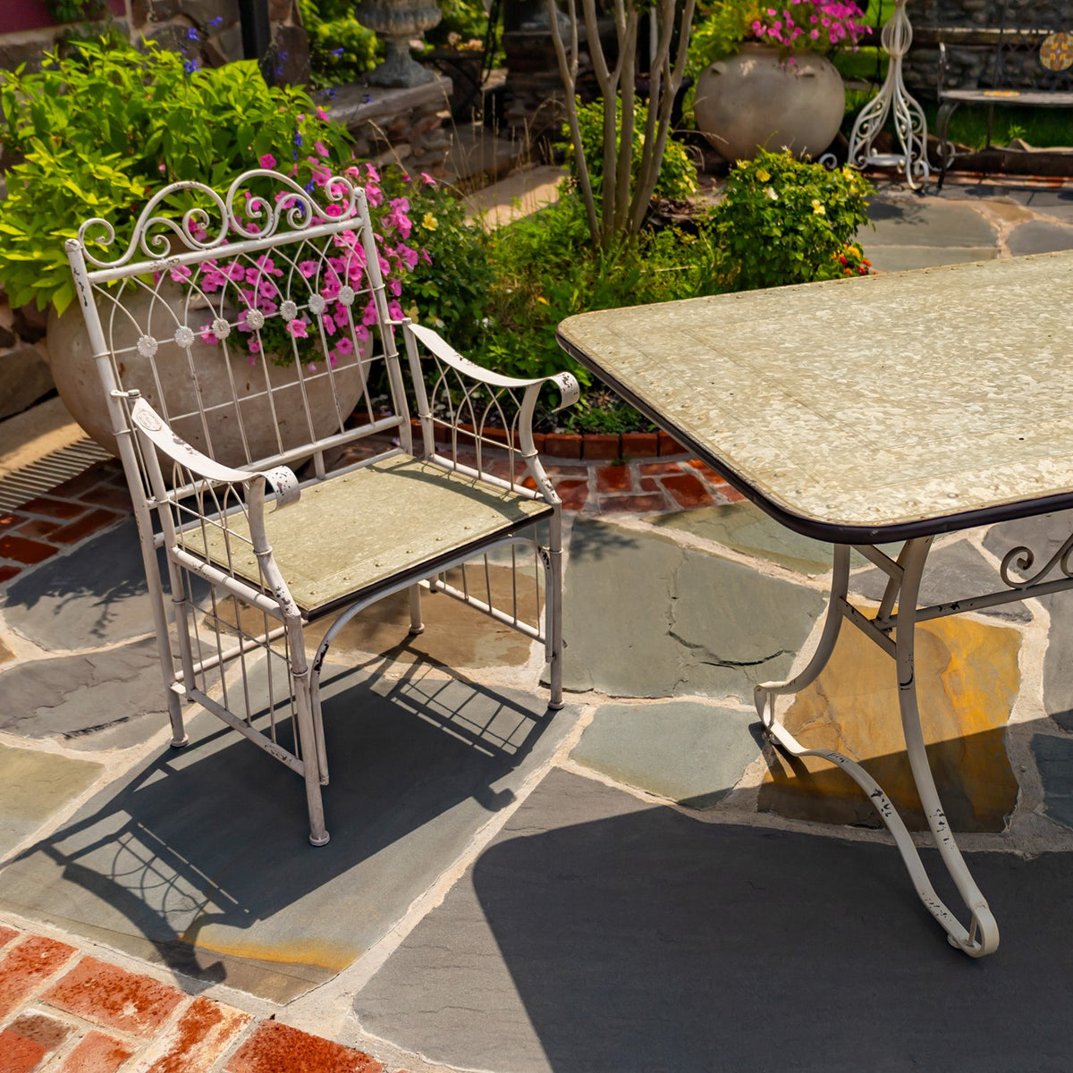 Close view of an ornate white metal chair beside the textured tabletop, with curved legs and arms visible.