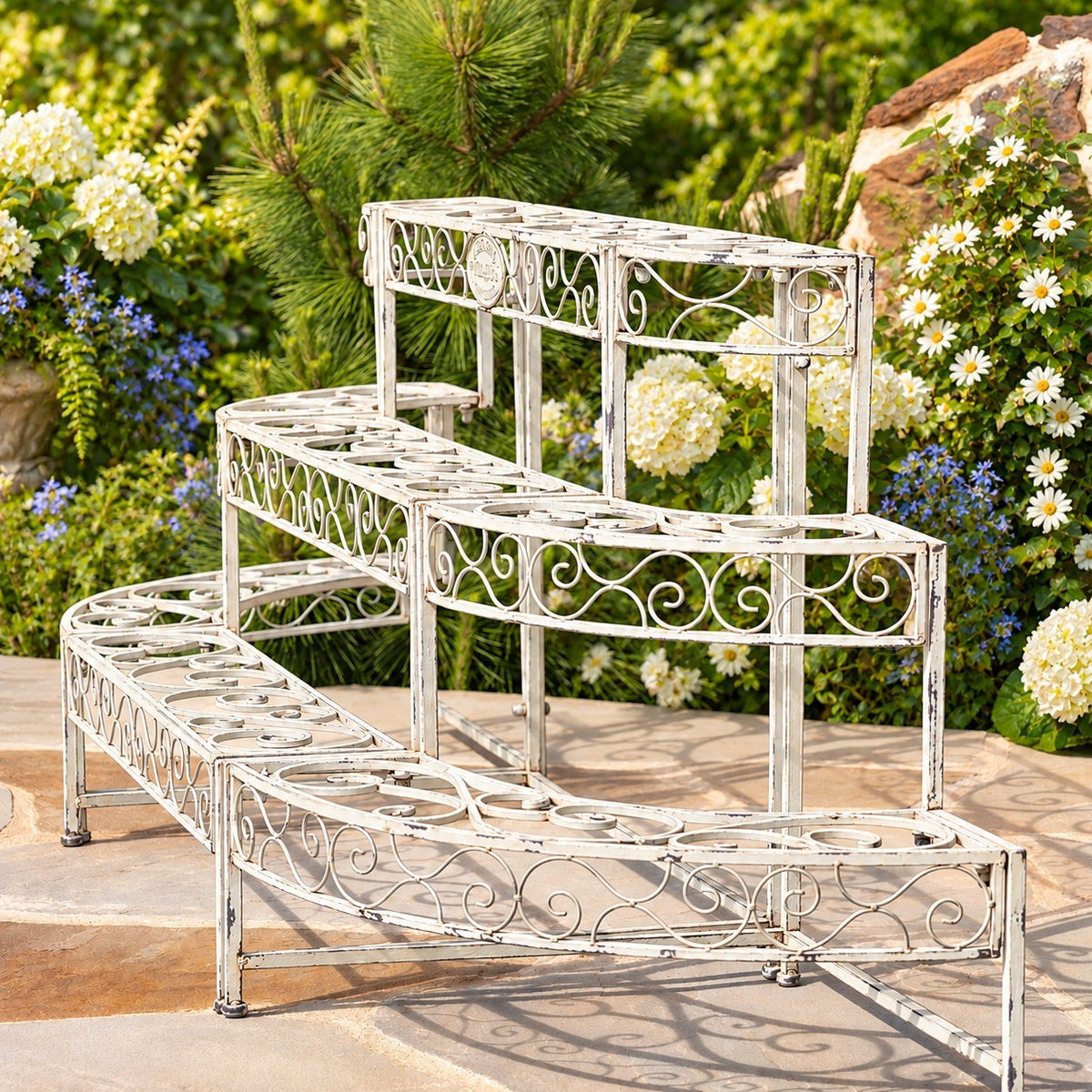 Three levels of oval plant platforms and curled metal detailing viewed diagonally in a garden.