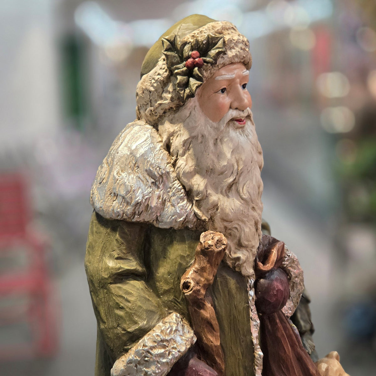 Close side view of Santa's green coat, textured hat and walking staff