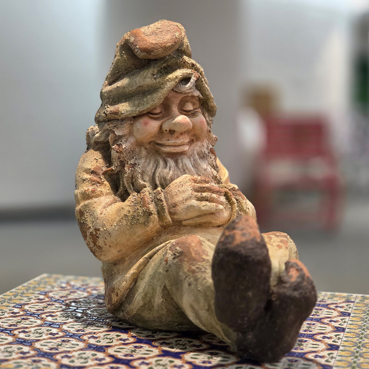 Sleeping garden gnome figurine shown seated from a slightly wider front angle