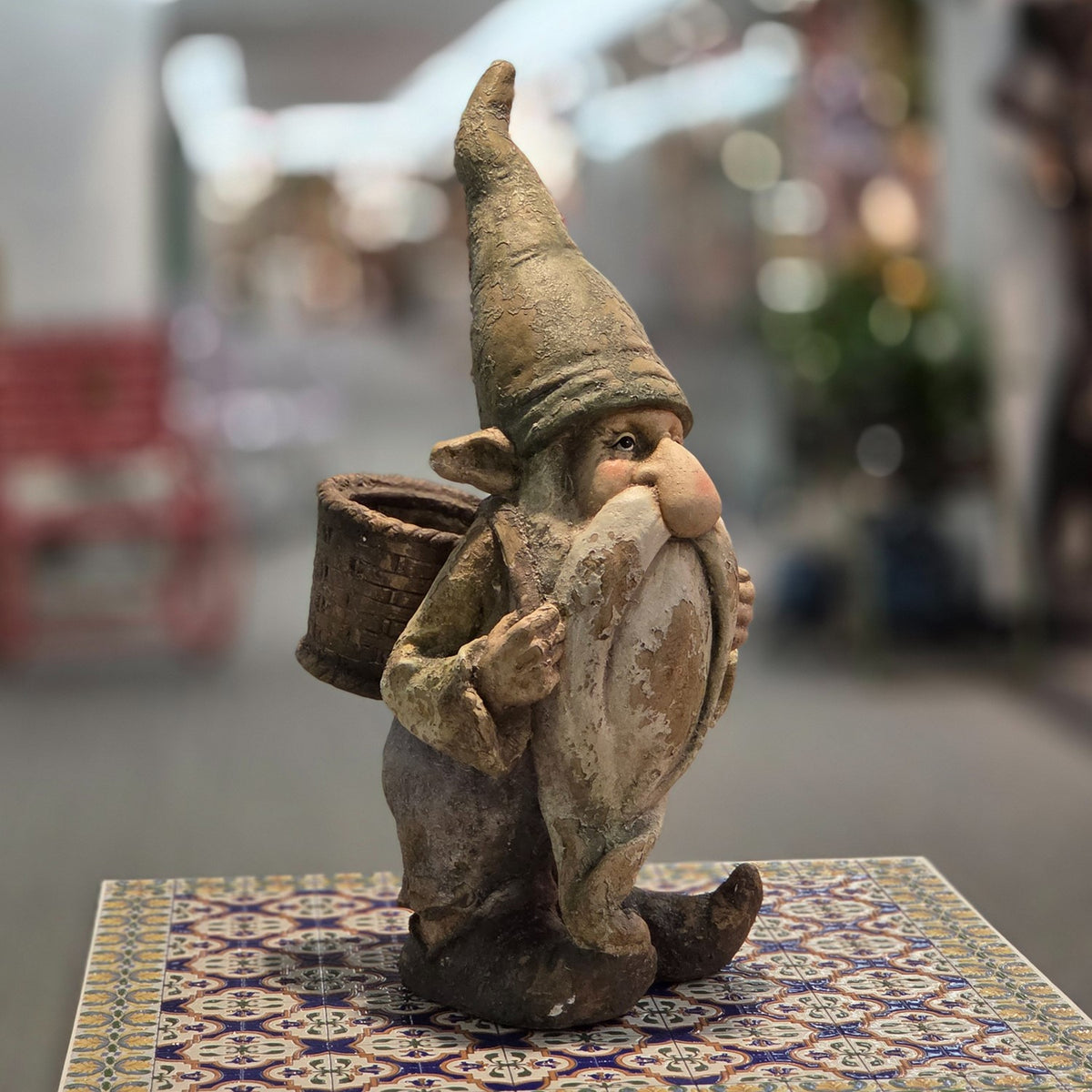 Distressed garden gnome with a woven-look back basket, shown from the opposite front angle