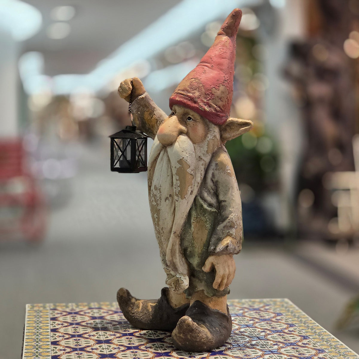 Angled side view of a rustic gnome holding a black lantern