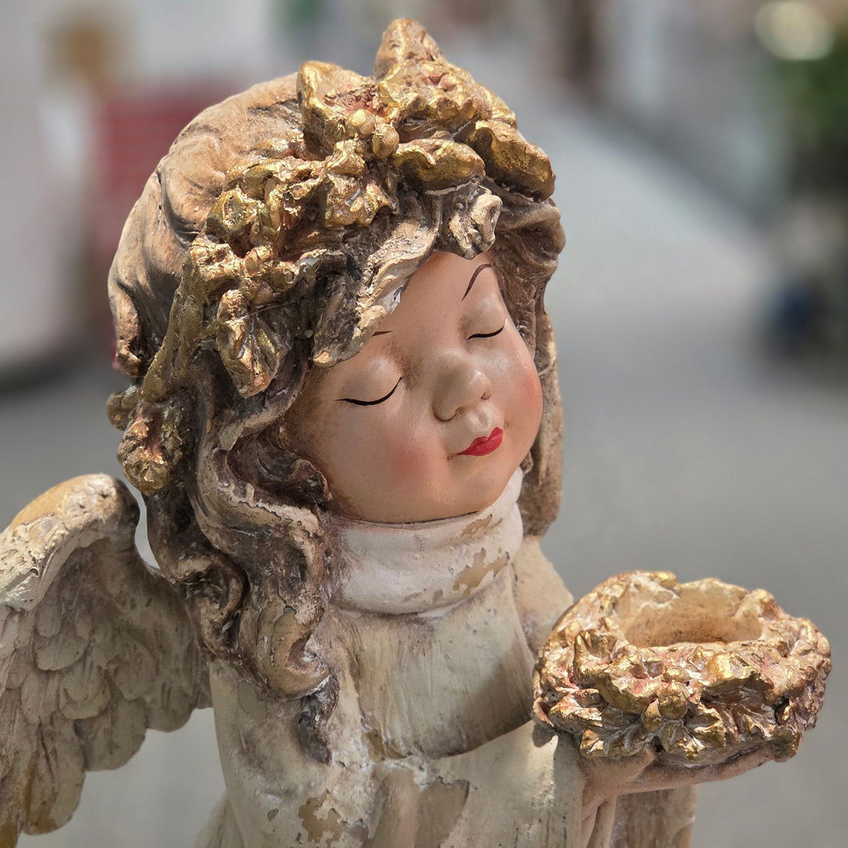 Close view of angel figurine's face, gold flower crown and bouquet