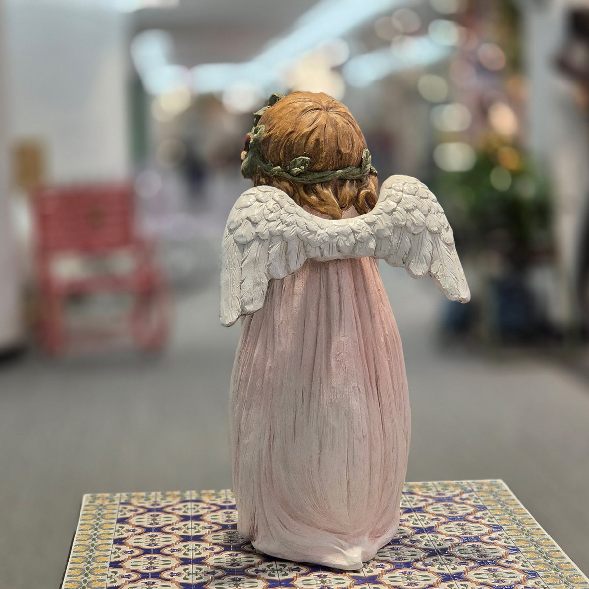 Rear view showing the angel figurine's white wings and flowing blush gown