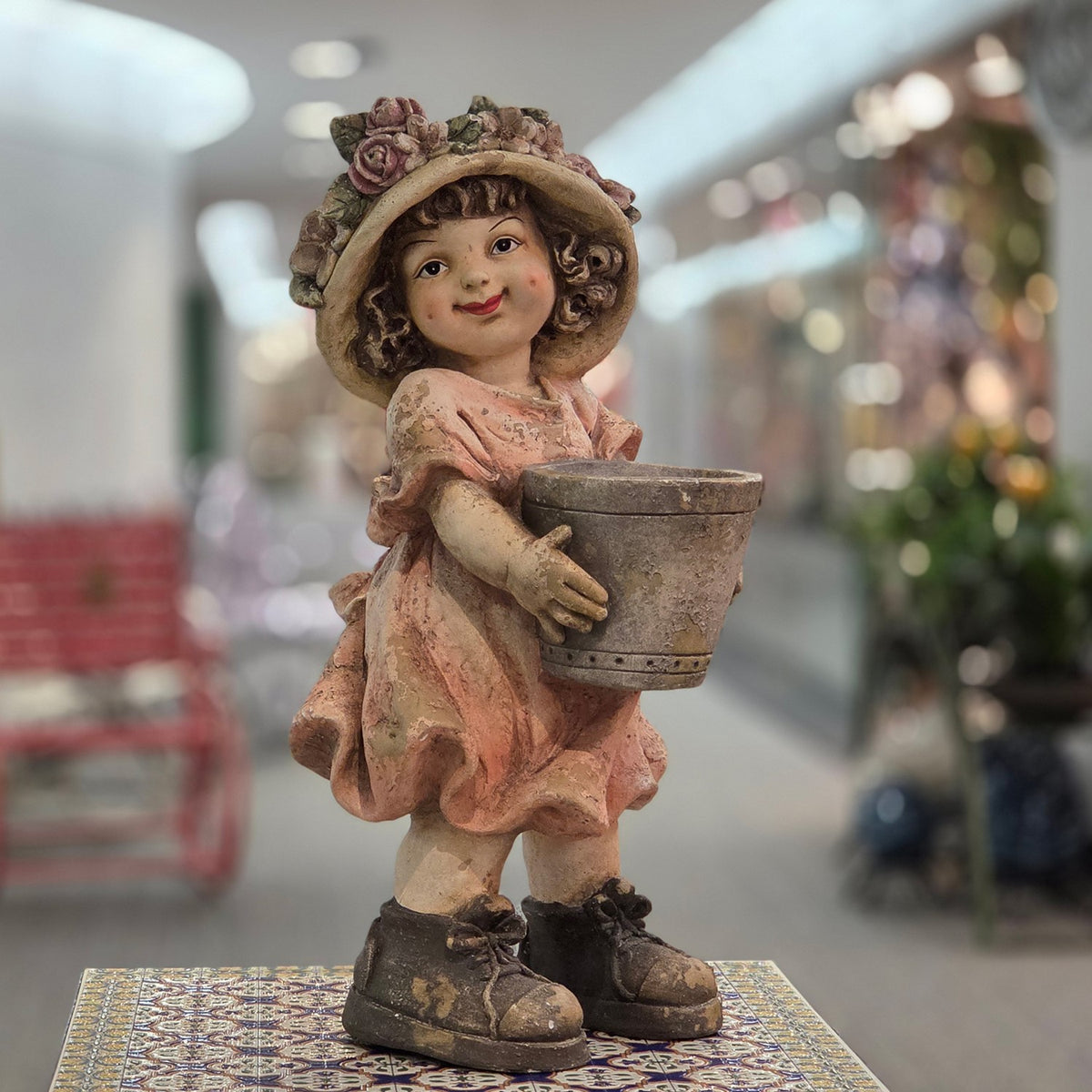 Pastel girl figurine holding an empty flowerpot, front view