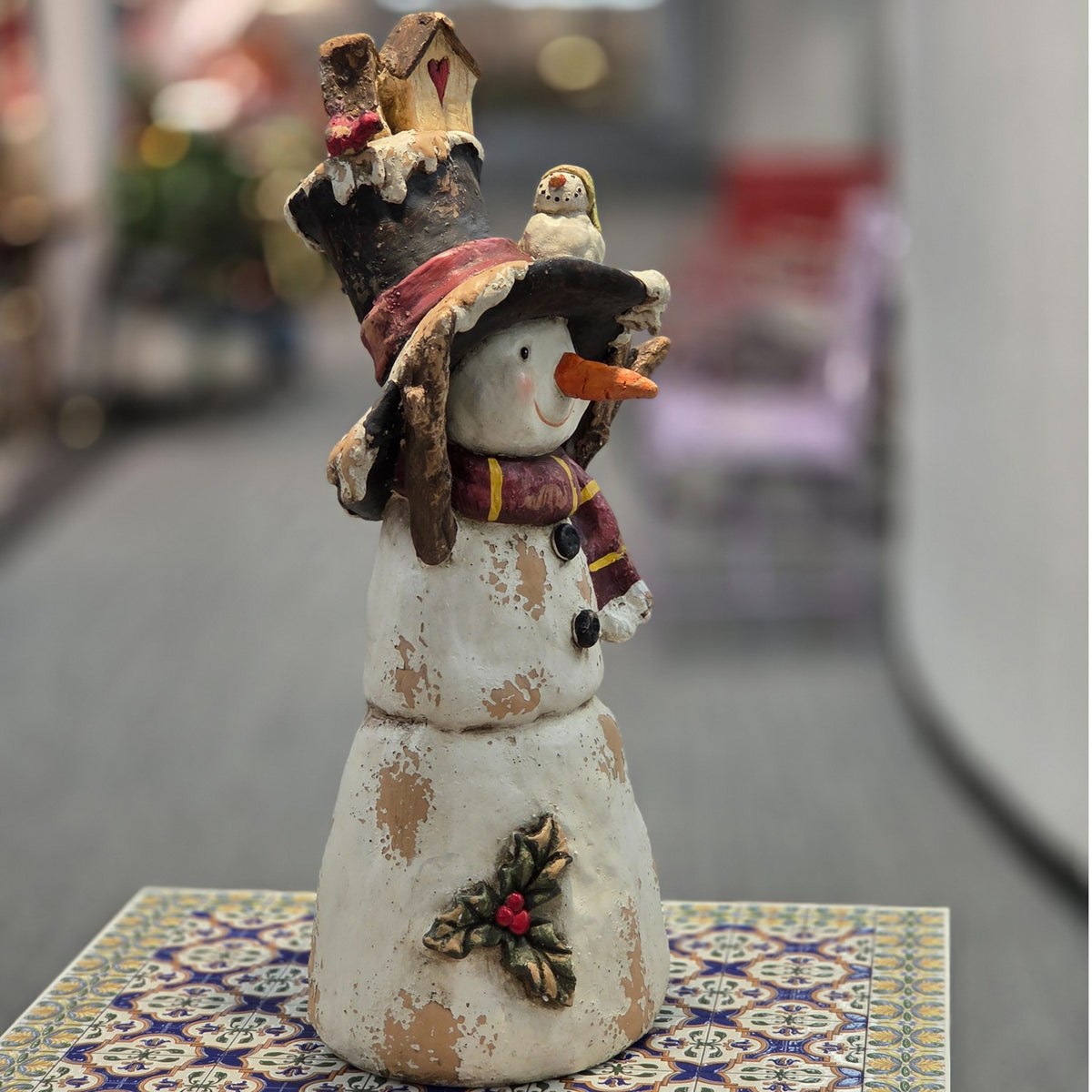 Distressed snowman figurine in a front three-quarter view on a table