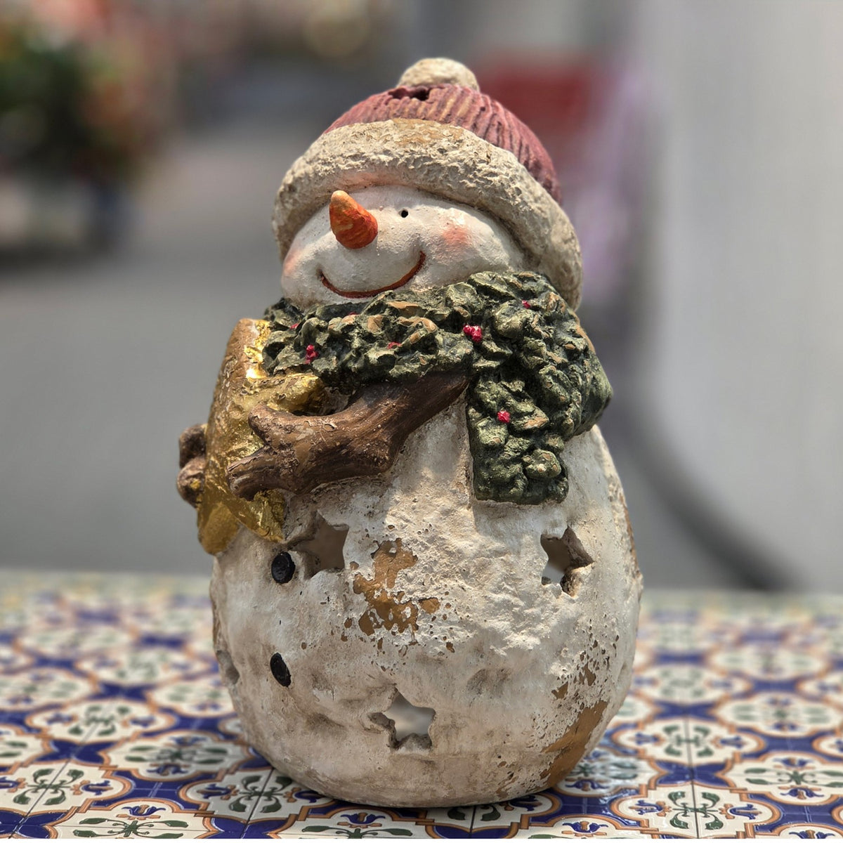 Snowman figurine with holly garland and star, shown from a front-side angle