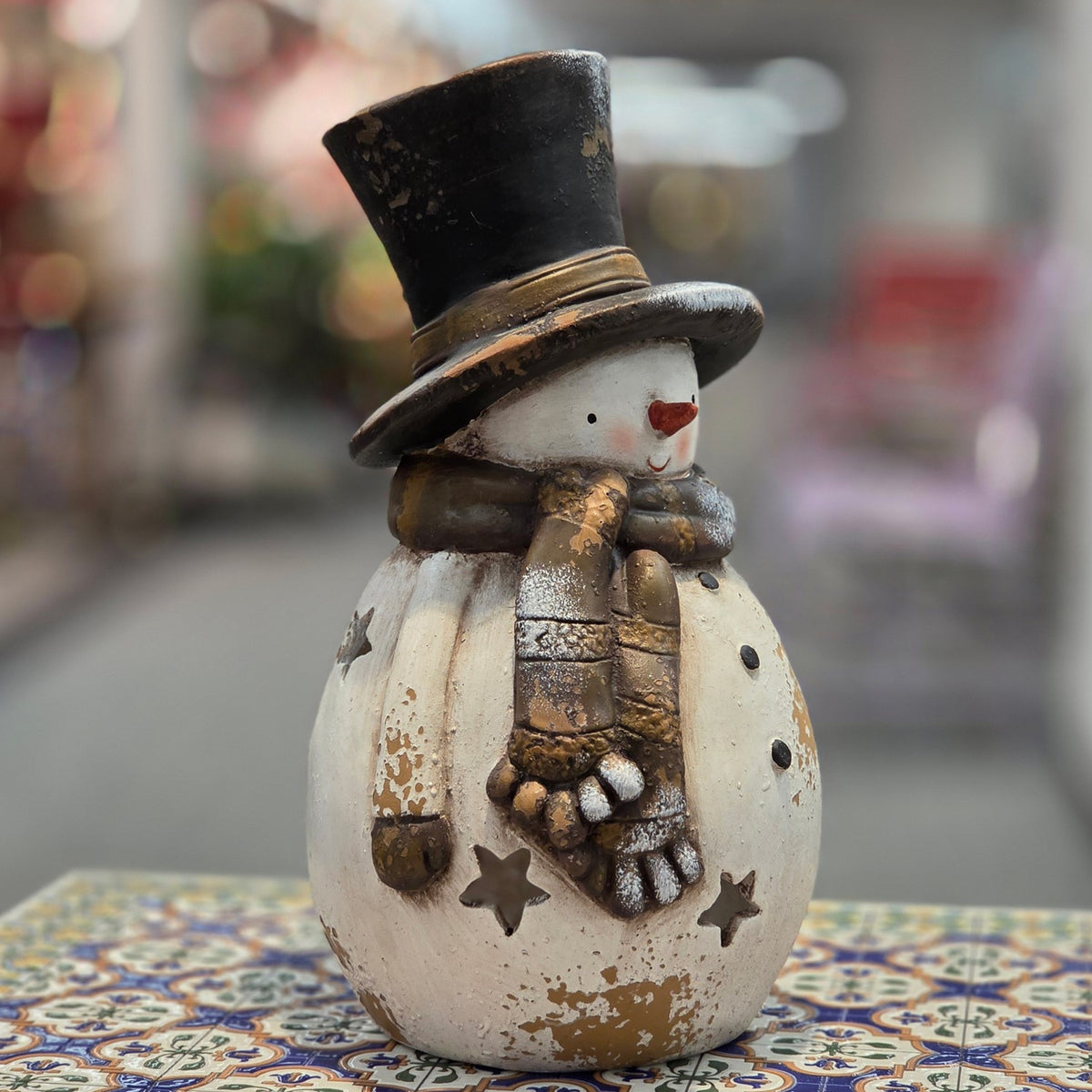 Snowman candleholder with scarf and star cutouts, turned to show its side