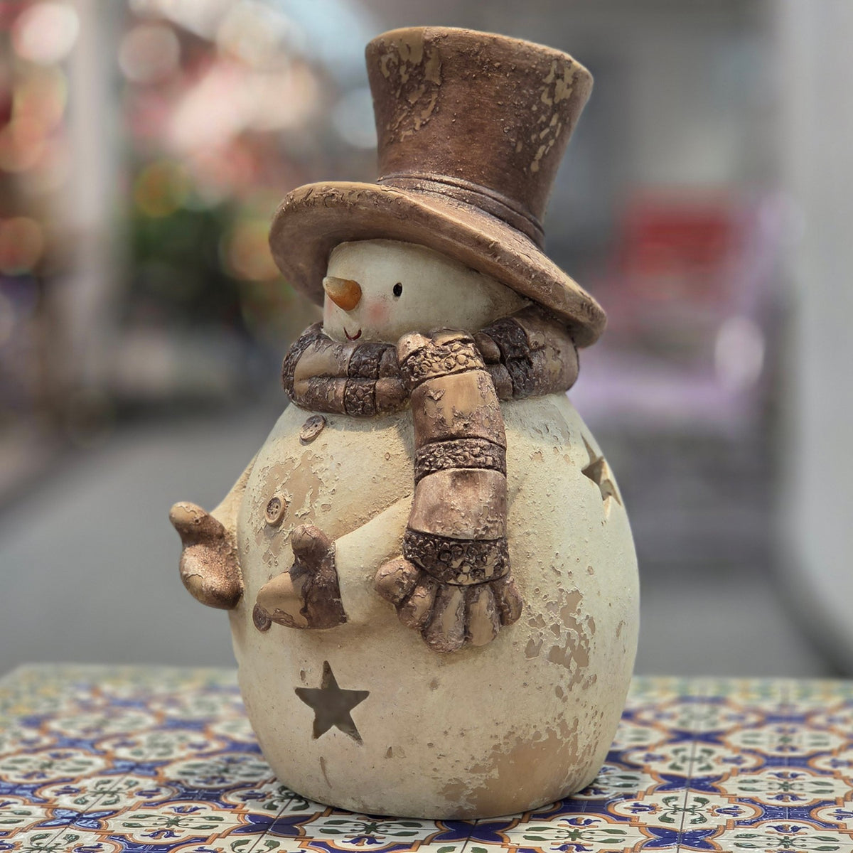The snowman candleholder is shown from another angle, with its scarf, buttons, outstretched arms, and star cutouts visible.