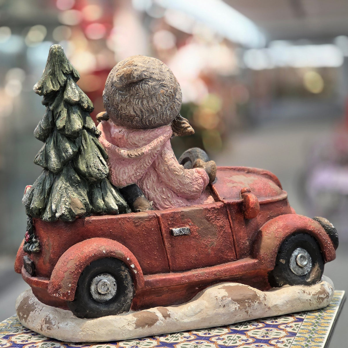 Rear view of a girl in a red truck with a Christmas tree