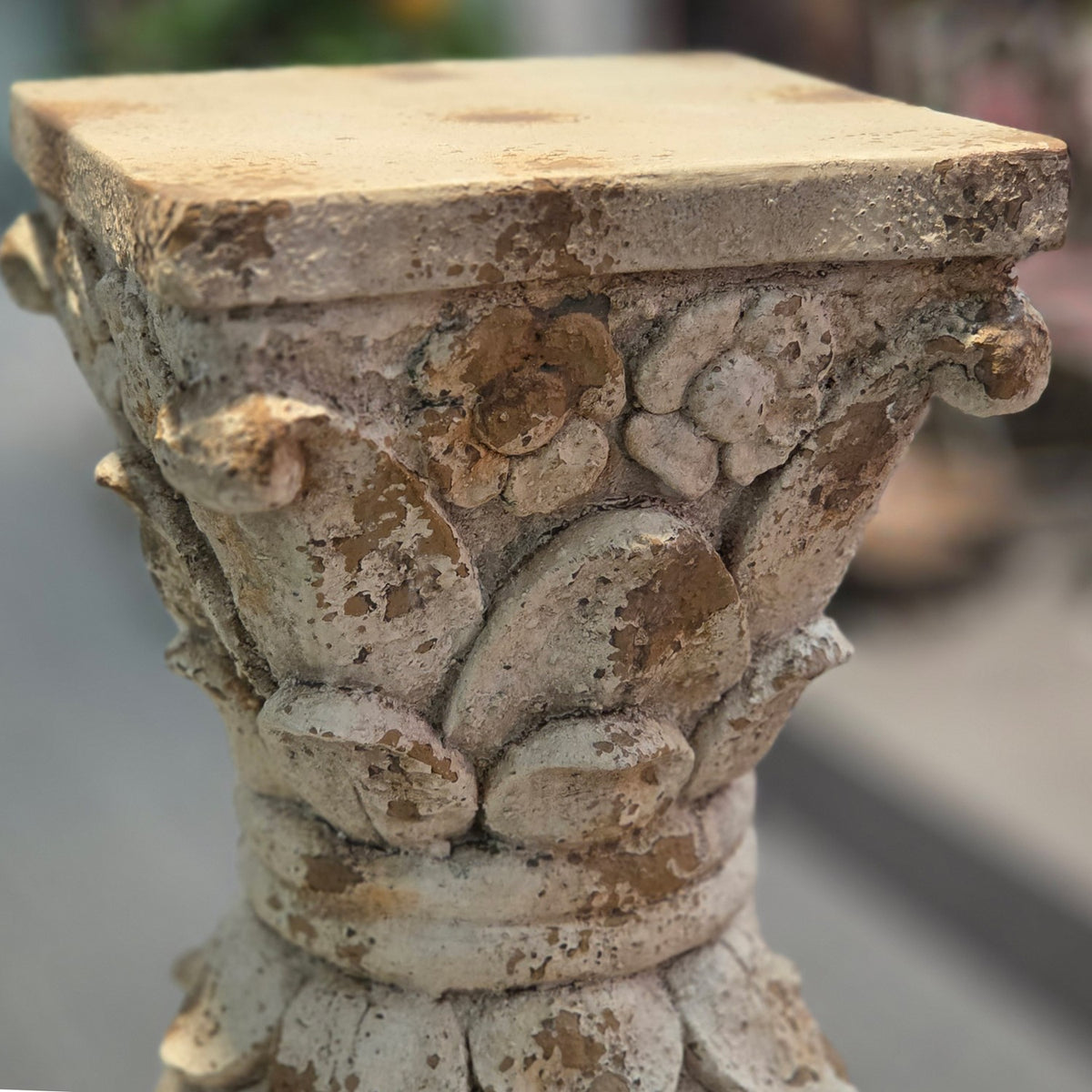 Close-up of the distressed carved upper section and flat top of the pedestal