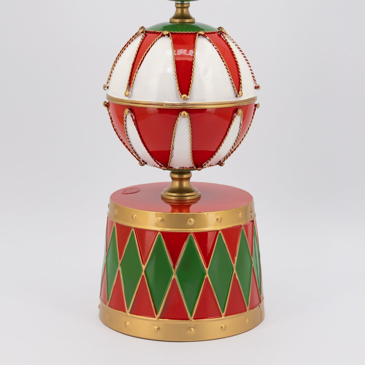 Close view of a large red-and-white bauble above a base decorated with red and green diamonds.