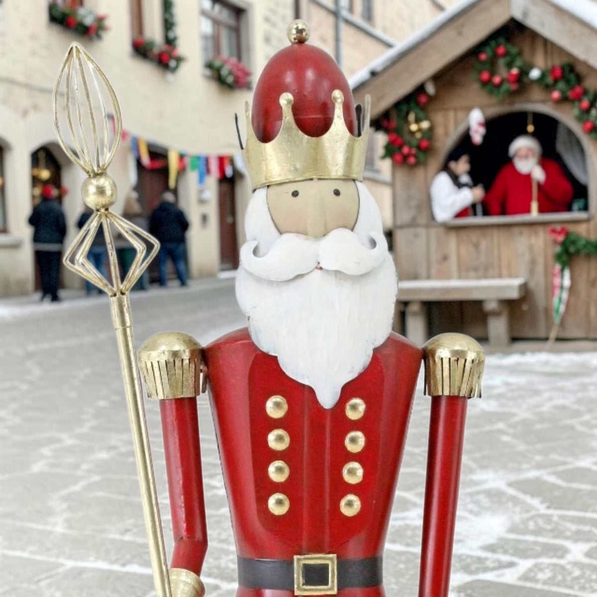 Close view of the figurine’s crowned face, white beard, red coat, and gold staff.