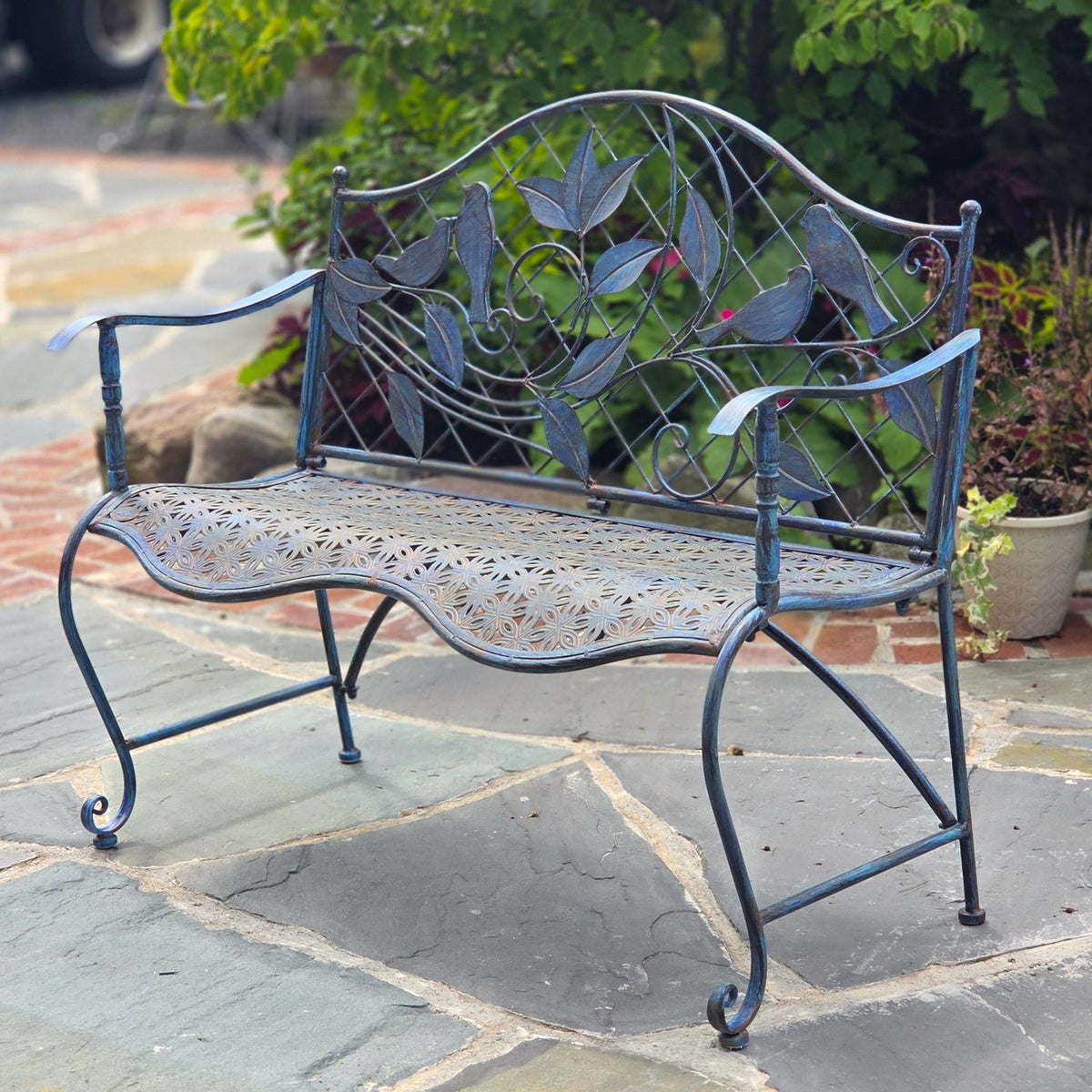 Angled view of a blue garden bench showing its openwork seat and curling metal legs.