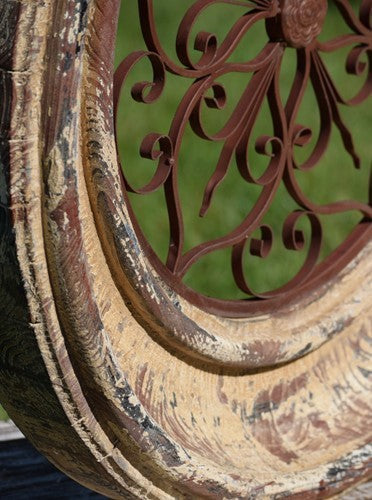 Close-up of distressed painted wooden frame and ornate iron scrollwork
