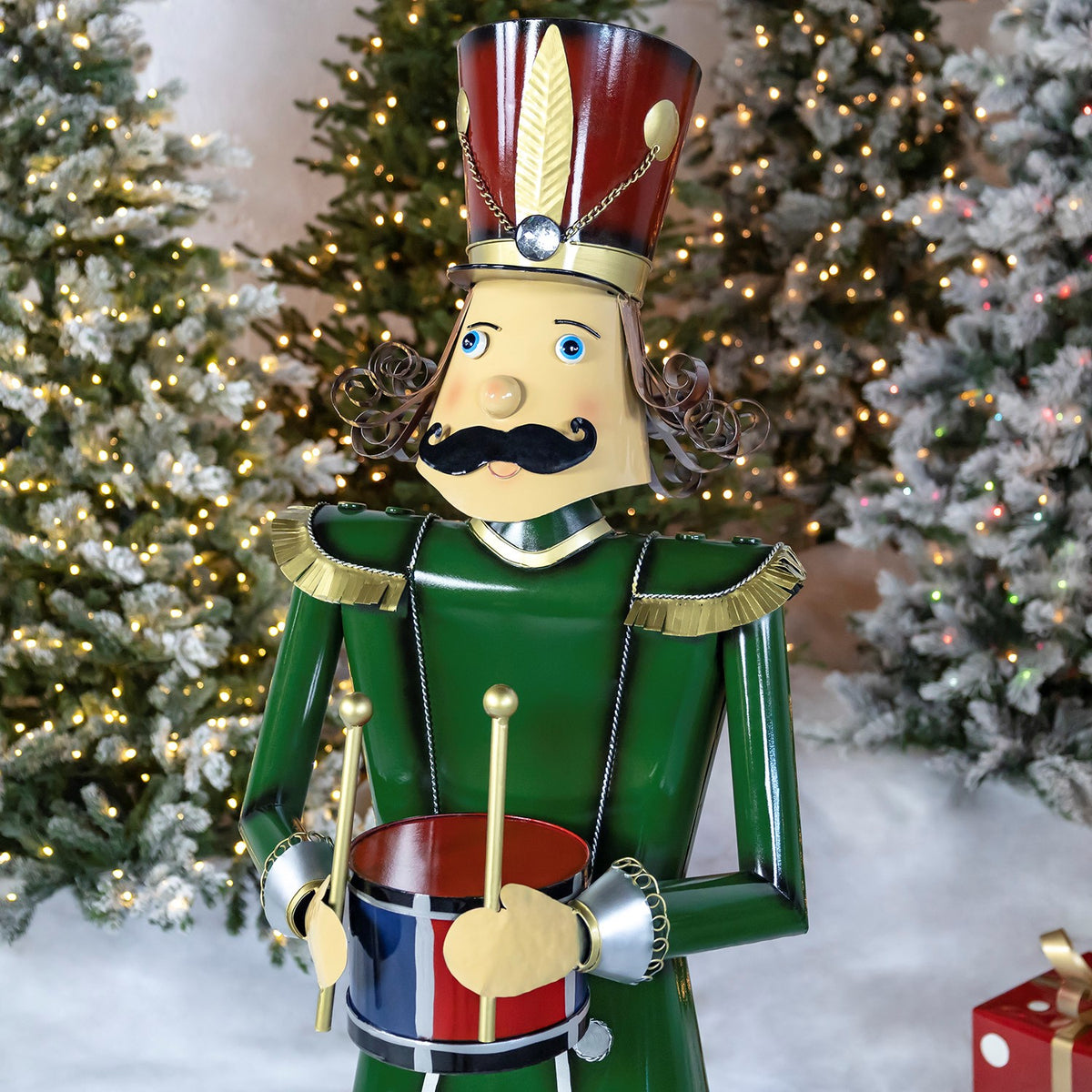 Angled view of the green nutcracker holding a drum among lit trees