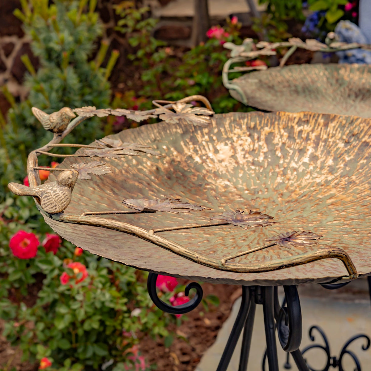 Angled close-up of the birdbath’s mottled bowl, leafy rim accents, and bird figures.
