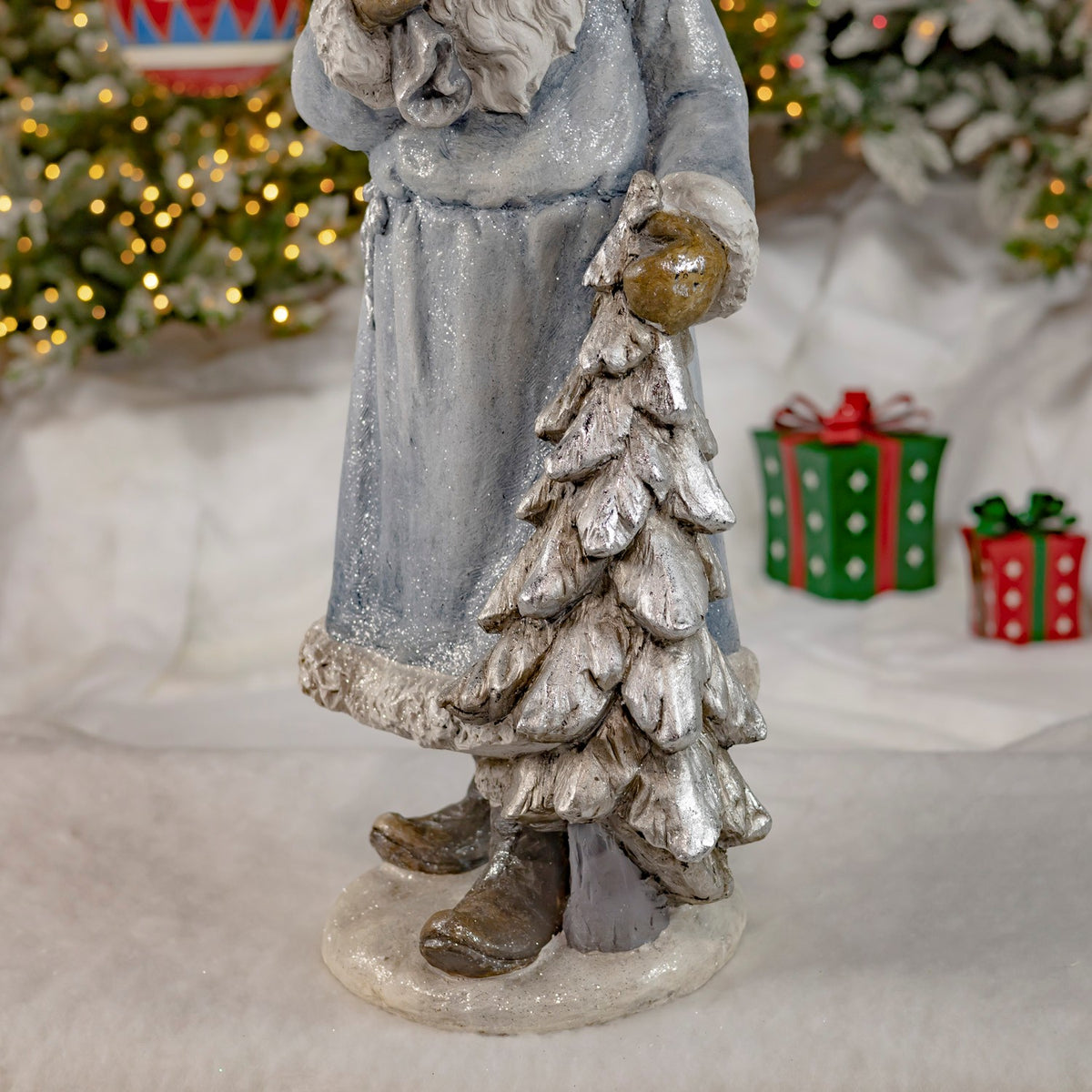Close view of the statue's silver-toned tree, cloak hem and boots