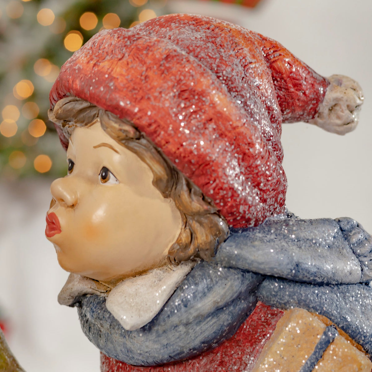 Close-up profile of the boy figurine in a red hat and blue scarf