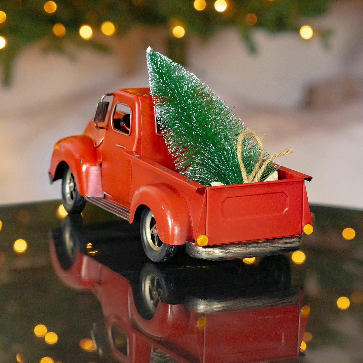 Rear view of the red pickup shows the evergreen resting in its open truck bed.