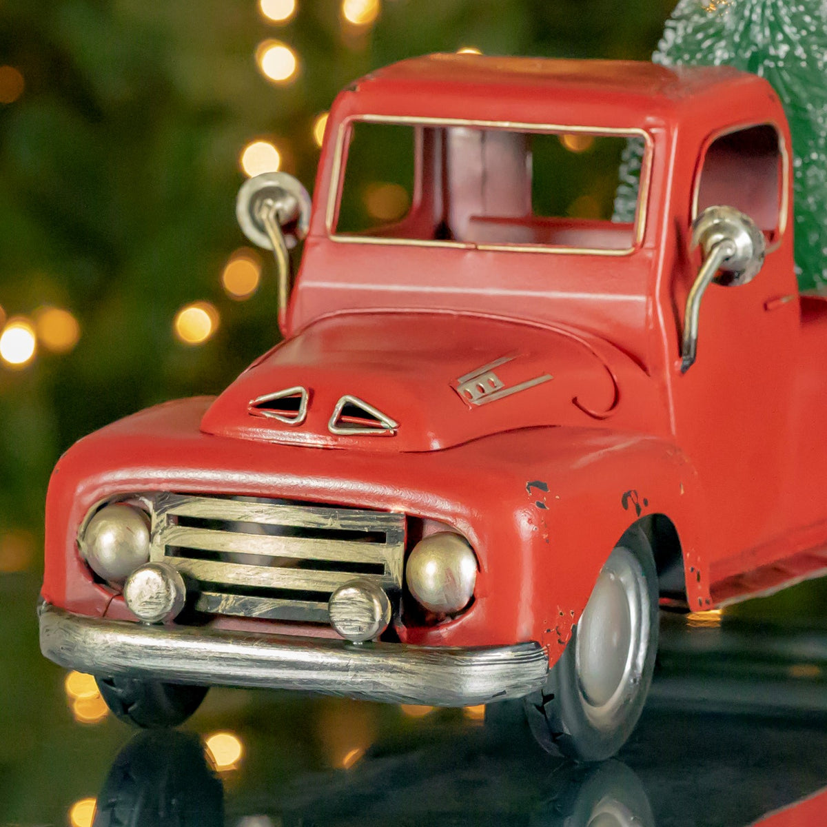 Close-up of the truck’s weathered red hood, windshield, round headlights, and silver grille.