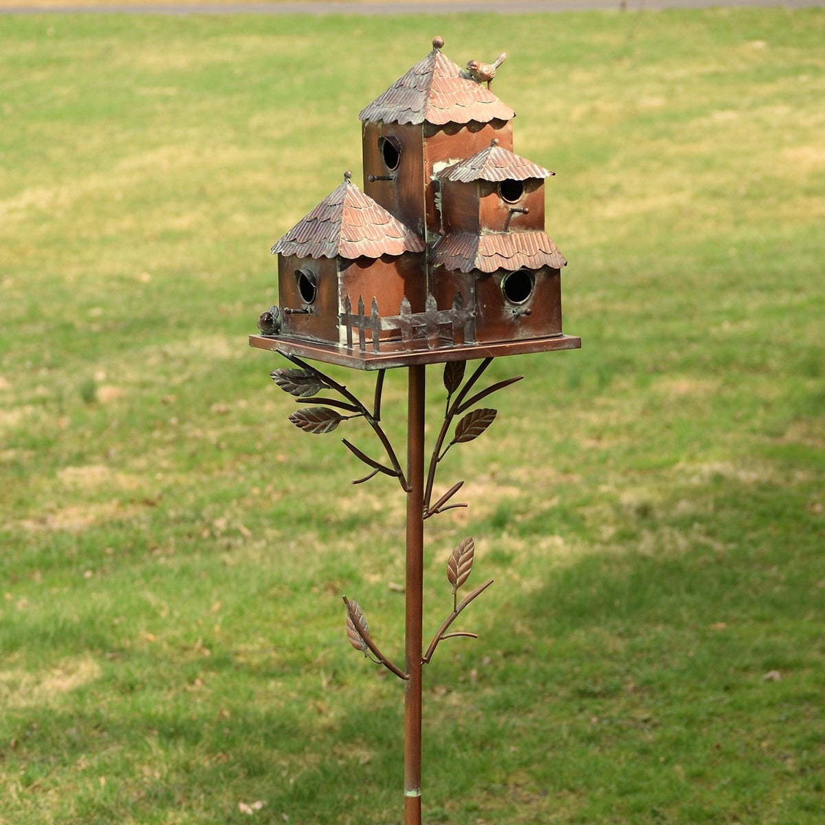 The birdhouse stake shown from another angle, revealing its three peaked-roof houses and decorative leaf branches.