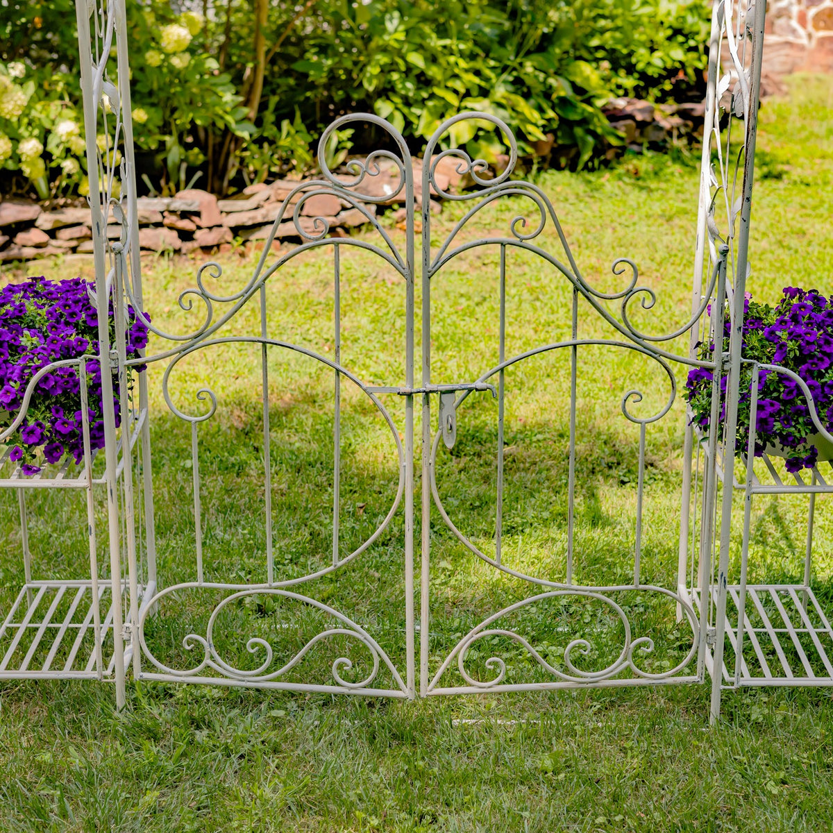 Close view of the iron gate scrollwork and side plant stands on grass