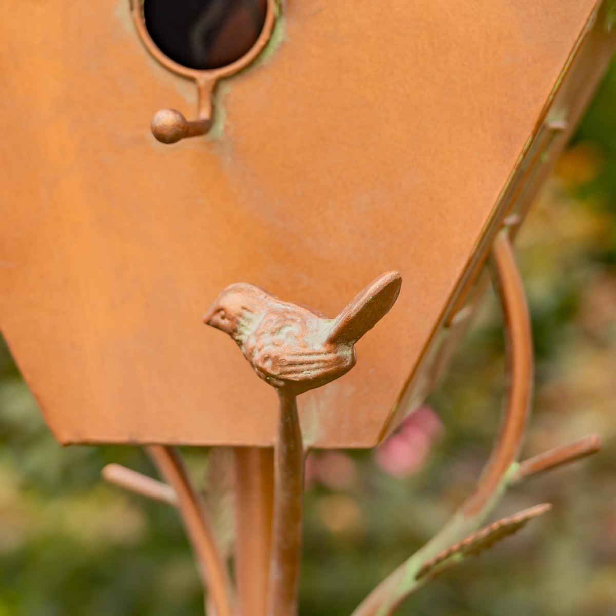 Close-up of a small bird detail on the copper birdhouse