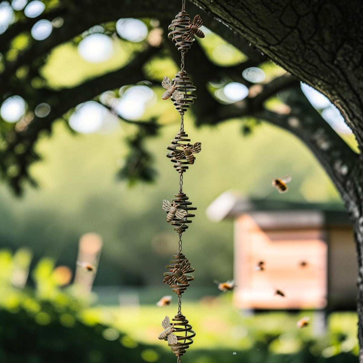 A long chain of small spiral cups and bee ornaments hangs beneath a tree canopy in a sunny garden.