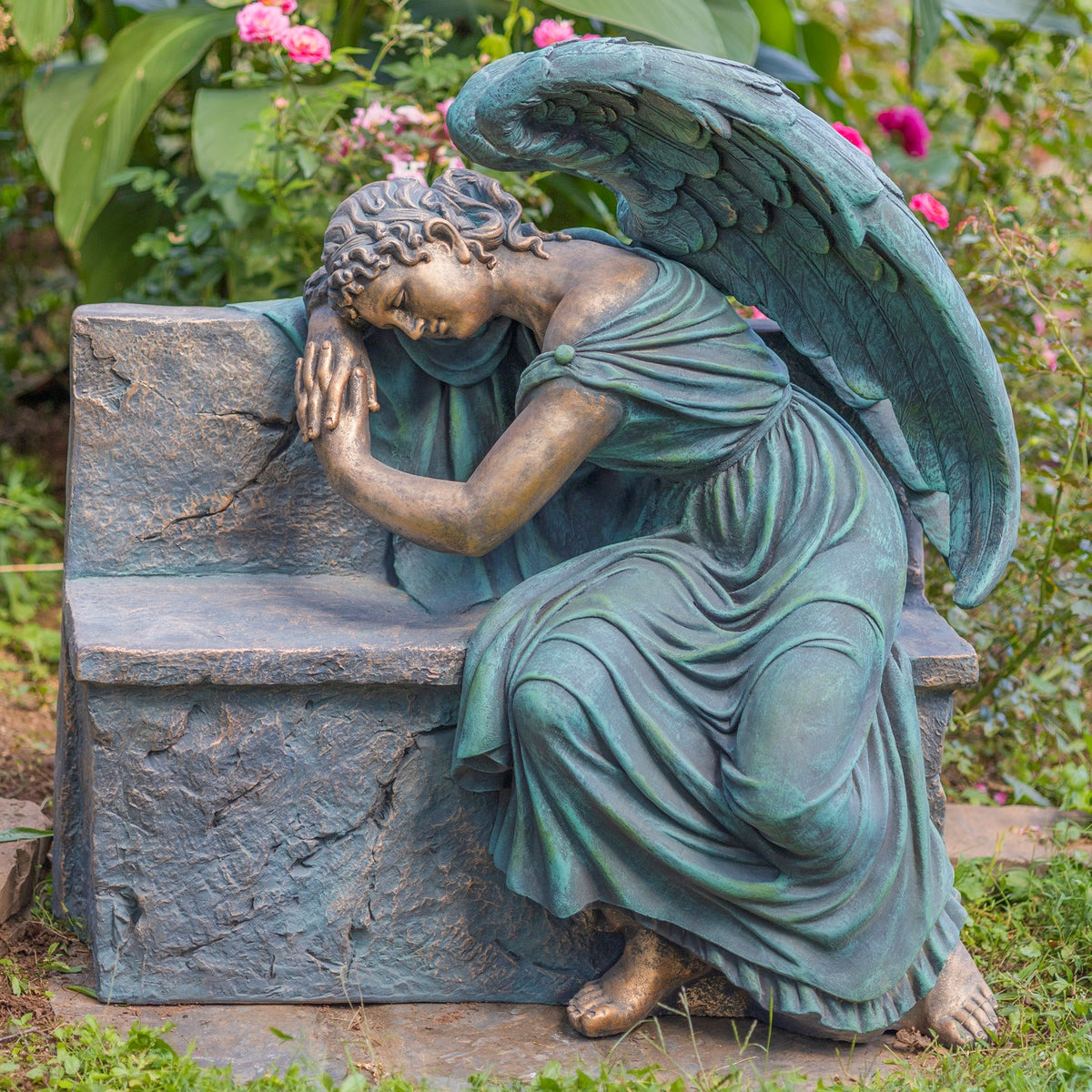 Seated angel leans over the bench, showing its flowing robe, full wings, and bare feet.