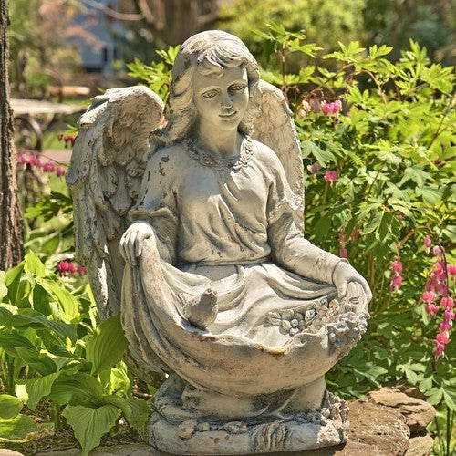 Front view of the seated angel with outstretched wings and birds resting in its gathered robe.