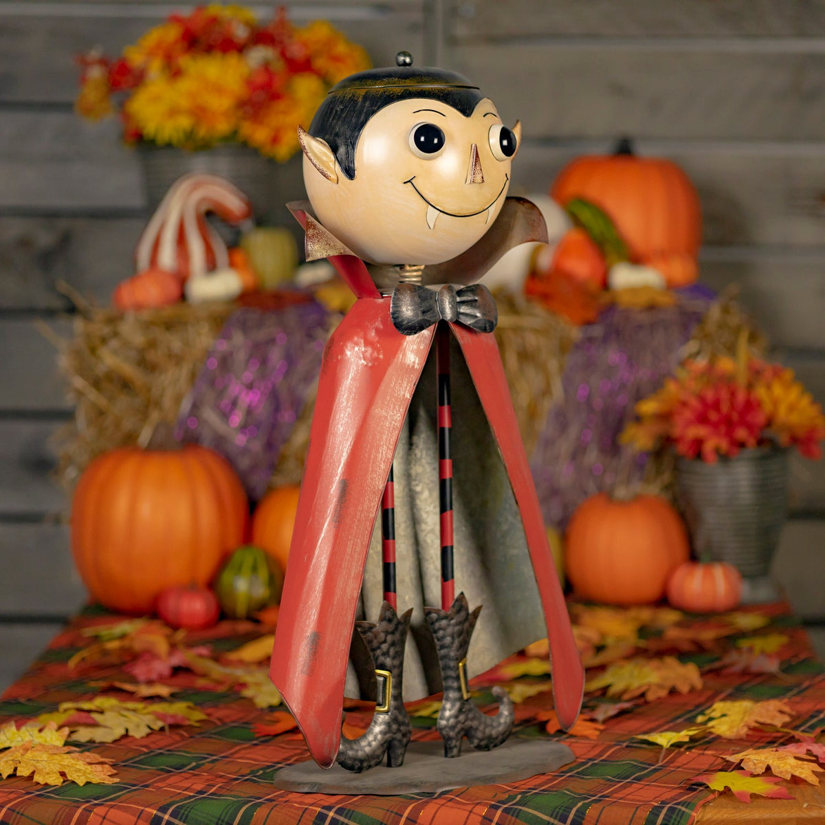 Full three-quarter view of the red-caped vampire figurine among Halloween pumpkins