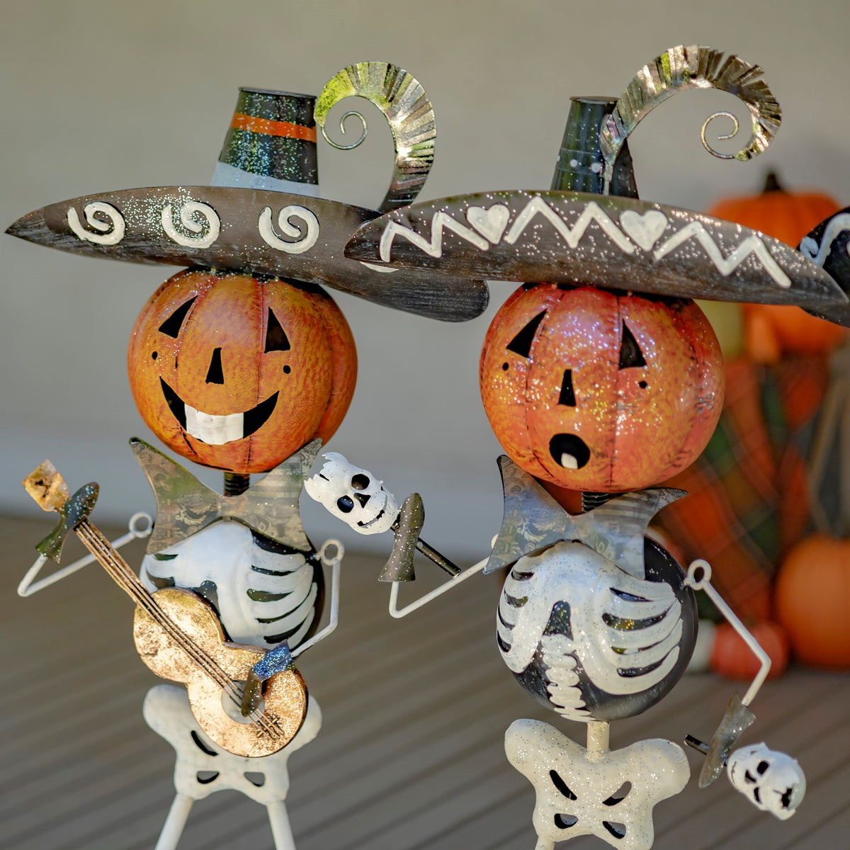 Two pumpkin-headed skeleton mariachi figurines, including one playing a guitar